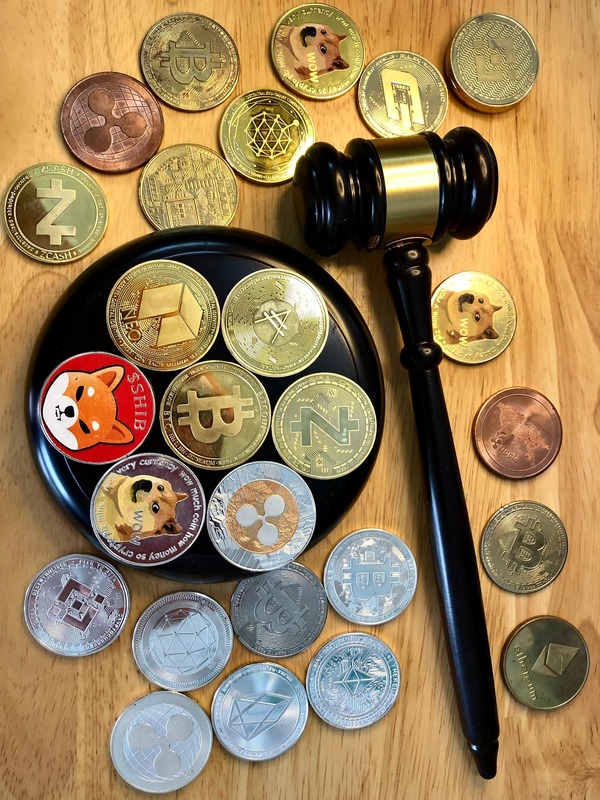 Assorted crypto coins with a judge gavel on a wooden table