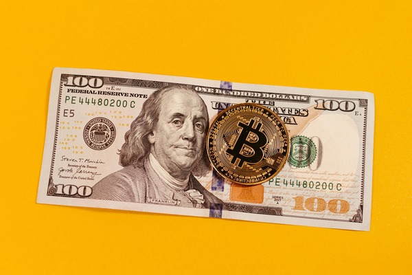 Bitcoin coin on a dollar banknote with a yellow background