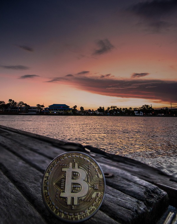 Bitcoin coin on a wooden pier at sunset