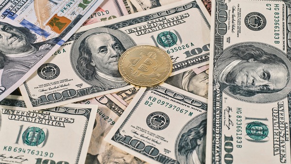 Bitcoin coin on top of US dollar banknotes