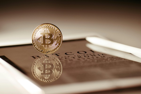 Bitcoin coin reflected on a dark tablet