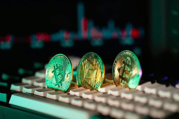Crypto coins on a keyboard lit by a green chart