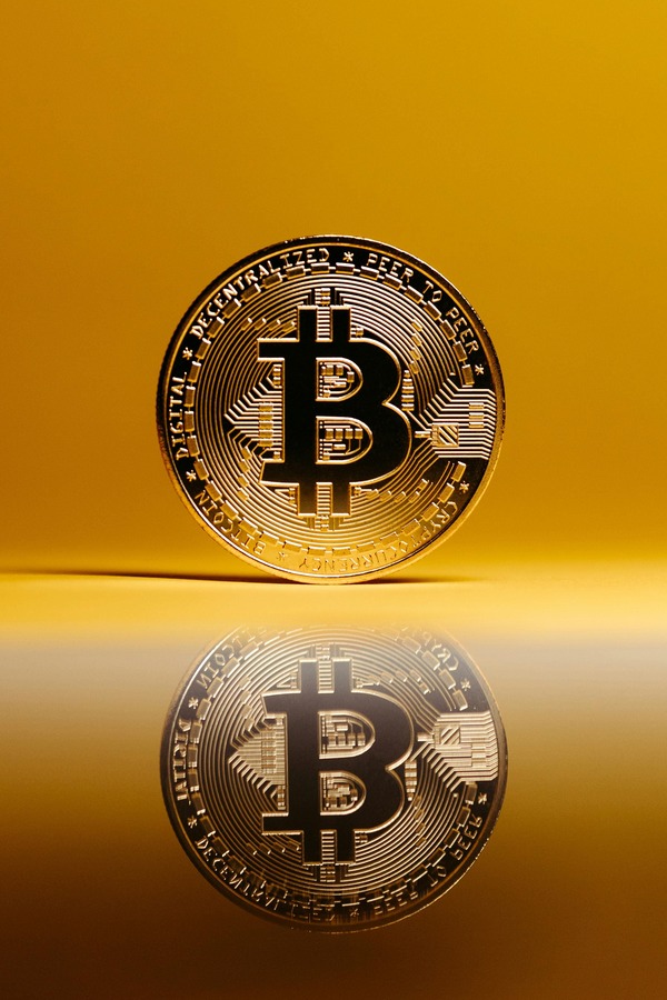 Gold Bitcoin coin reflected on a golden surface