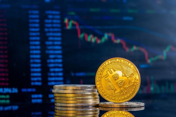 Gold Bitcoin coins over a stock ticker display
