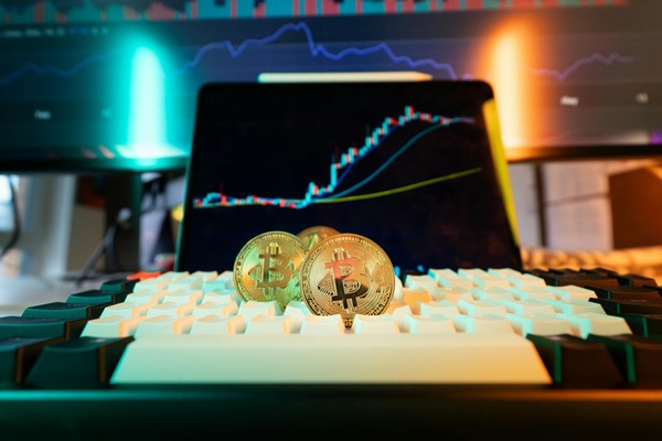 Gold coins on a keyboard before a glowing chart