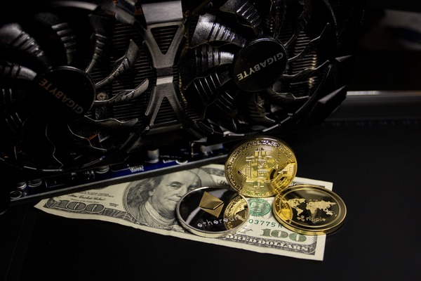 Gold coins on banknotes in front of a graphics card