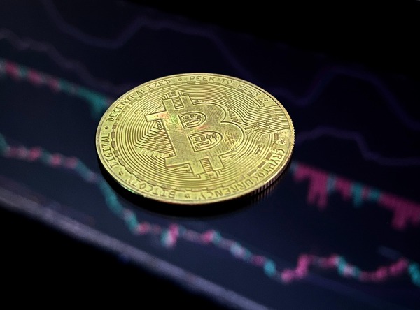 Gold crypto coin over a dark trading chart