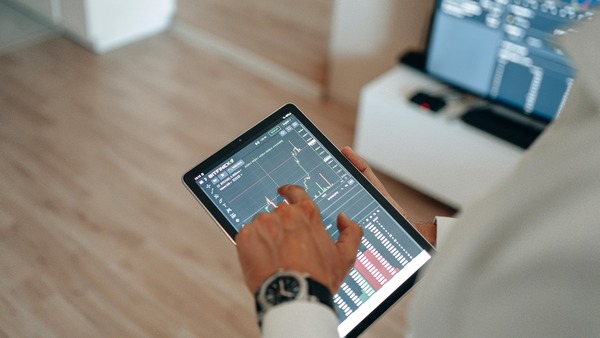 Hand using a tablet with a price chart