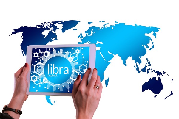 Hands holding a tablet with digital currency over a world map