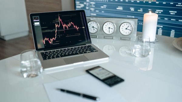 Laptop with a trading chart beside world clocks