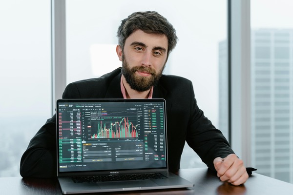 Man working on a laptop with a trading chart