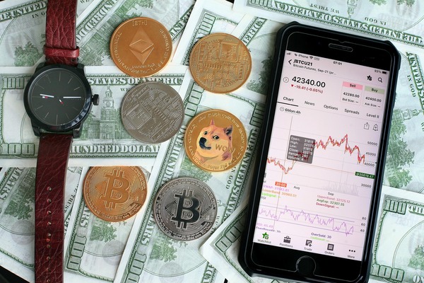 Smartphone with a crypto app, a watch and coins on banknotes